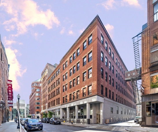 Front view of a multi-story brick building on a street corner.