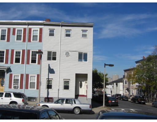 Front view of a multi-story residential building with white siding and red shutters.