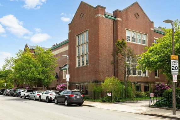 Front view of a brick building with large windows and decorative architectural features.