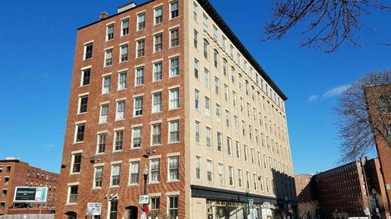 Front view of a multi-story building with a mix of brick and light-colored facade.