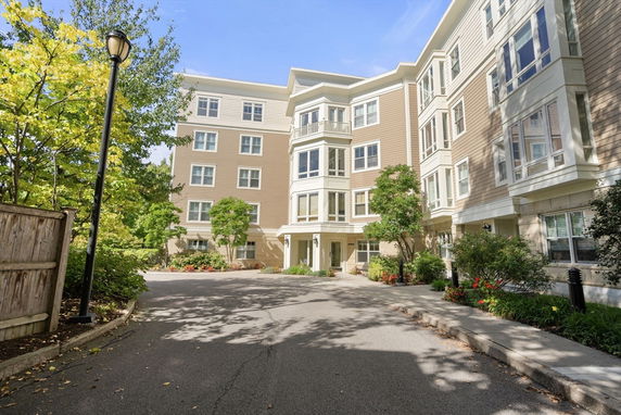 Front view of a multi-story residential building with landscaped entrance.