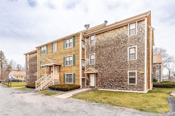 Front view of a multi-story apartment building with wood siding.