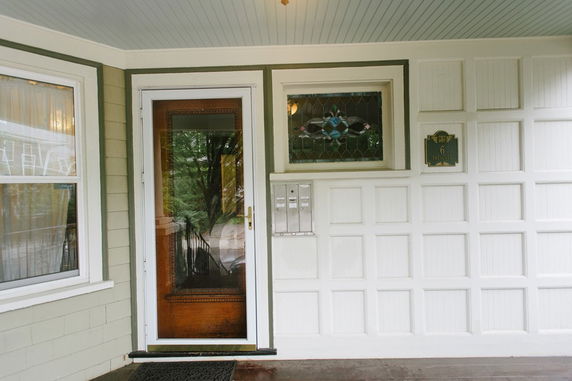 Front entrance of a house with a glass door and a small stained glass window above it.