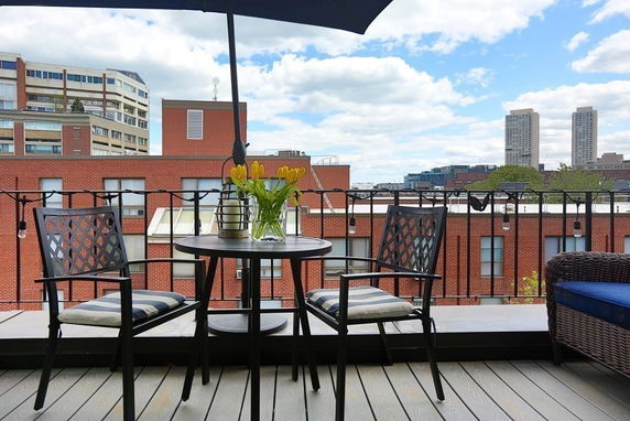 View of surrounding buildings and skyline from a balcony with outdoor furniture.