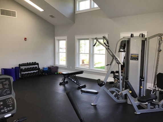 Interior view of a gym area with exercise equipment and windows.