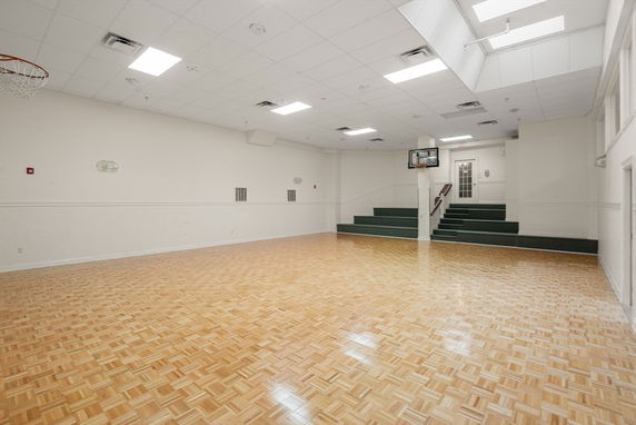 Indoor play area with a basketball hoop and wooden floor.