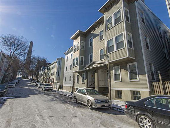 Front view of a multi-story residential building on a sloped street.