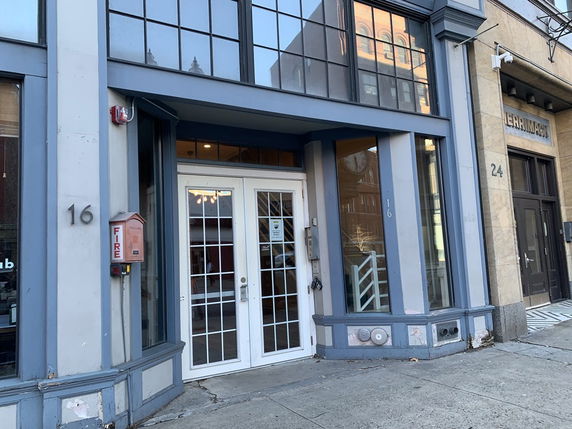 Front view of a commercial building with large windows and a double glass door entrance.