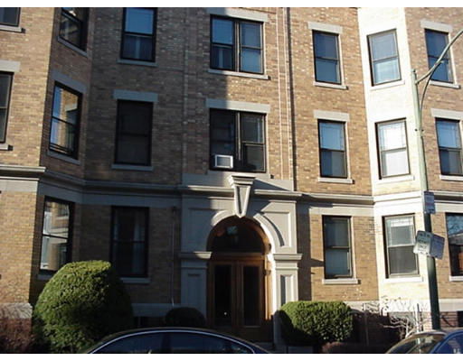 Front view of a multi-story brick building with multiple windows and an arched entrance.