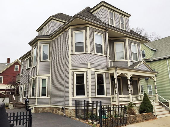 Front view of a multi-story house with detailed window trim and a small porch.