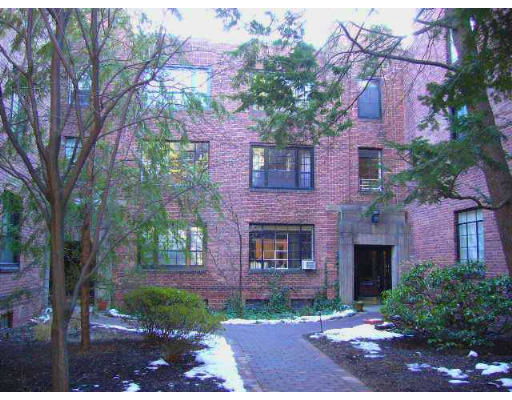 Front view of a brick apartment building with multiple windows and an entrance.