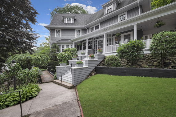Front view of a multi-story house with a porch and steps leading to the entrance.