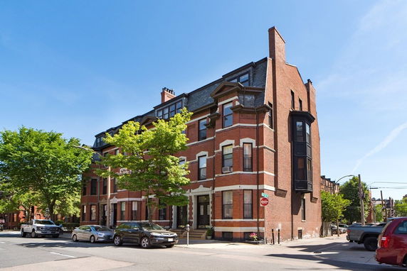 Front view of a multi-story brick building with large windows and a corner entrance.