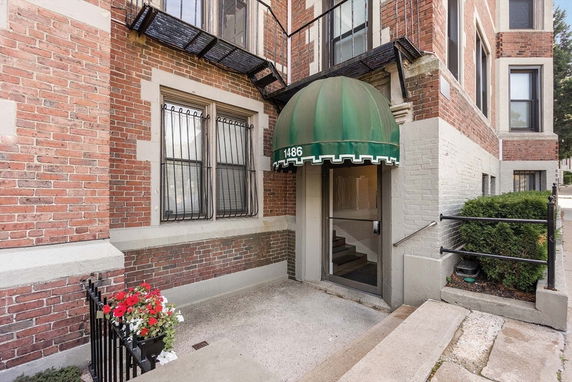 Entrance view of a brick building with a green awning above the doorway.