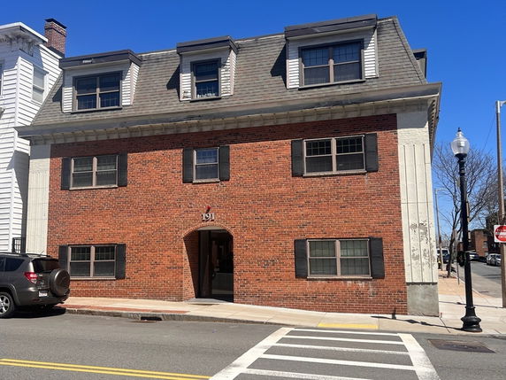 Front view of a three-story brick building with dormer windows.