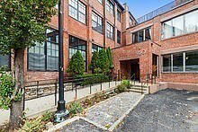 Front view of a brick multi-story building with large windows.