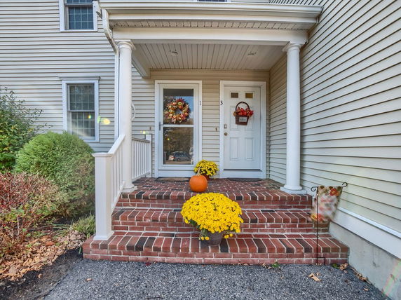 Front view of a house entrance with brick steps and columns.