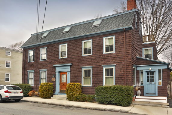 Front view of a two-story house with a steep roof and multiple windows.