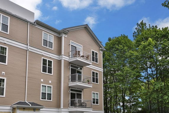 Front view of a multi-story building with balconies and large windows.