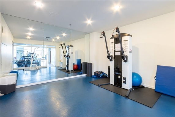Interior view of a gym area with exercise equipment and mirrors.