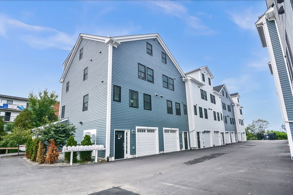 Front view of a multi-story residential building with garages on the ground level.