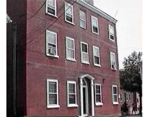 Front view of a three-story brick building with multiple windows.