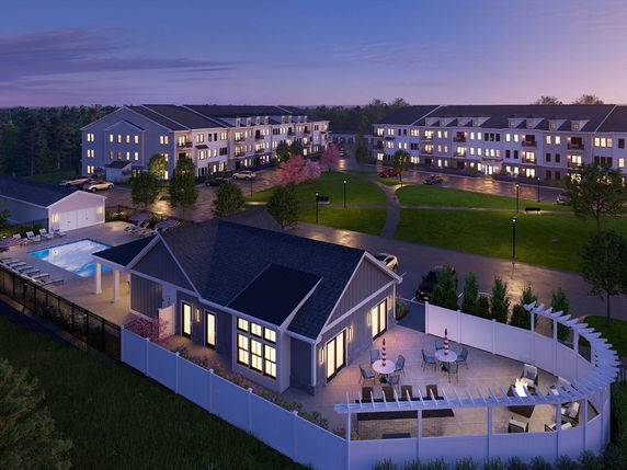 Panoramic view of a residential complex with illuminated buildings and swimming pool area at dusk.