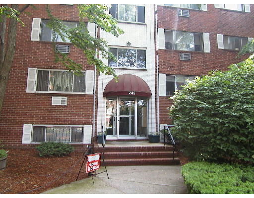 Front view of a multi-story brick apartment building with an awning over the entrance.