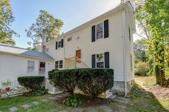 Front view of a two-story house with white siding and black shutters.