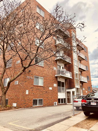 Front view of a multi-story brick apartment building with balconies.