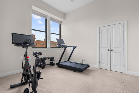 Room with exercise bike and treadmill near a window.