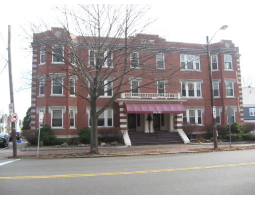 Front view of a three-story brick building with a central entrance and awning.