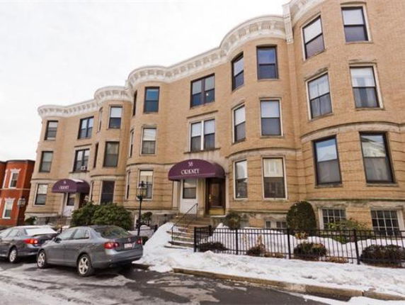 Front view of a brick multi-story building with bay windows and awnings.