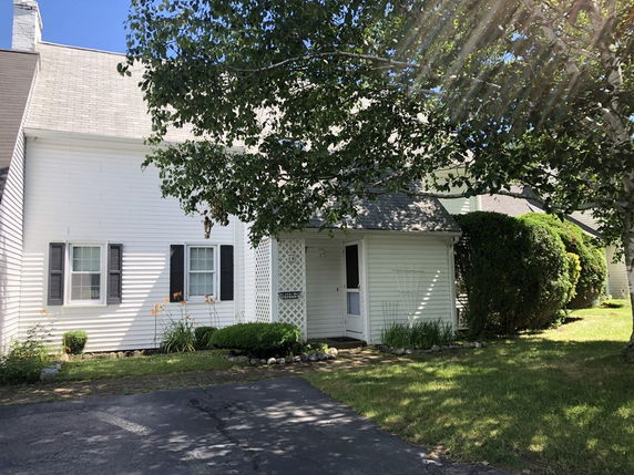 Front view of a white single-story house with dark shutters and a small porch entrance.