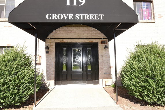 Front view of a building entrance with a black awning and double doors.