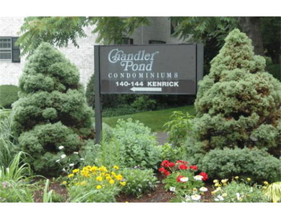 Entrance sign of Chandler Pond Condominiums with surrounding greenery.