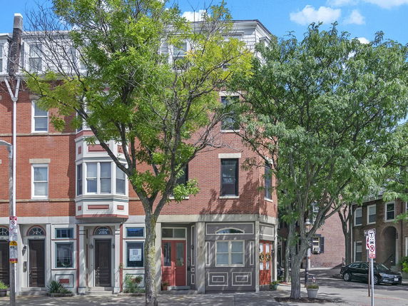 Front view of a multi-story brick building with large windows and decorative stone work.