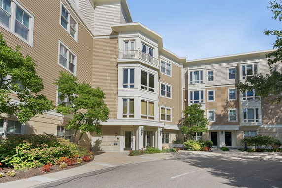 Front view of a multi-story residential building with beige siding and multiple windows.