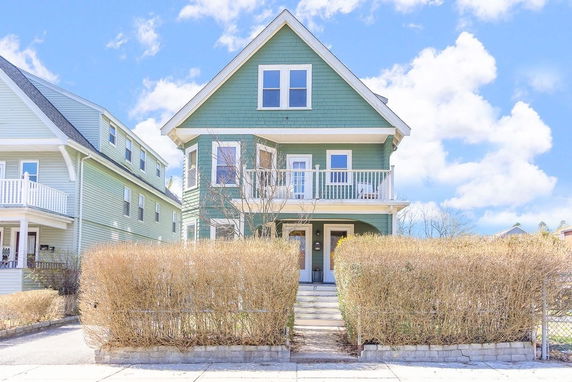 Front view of a two-story house with a balcony and green siding.