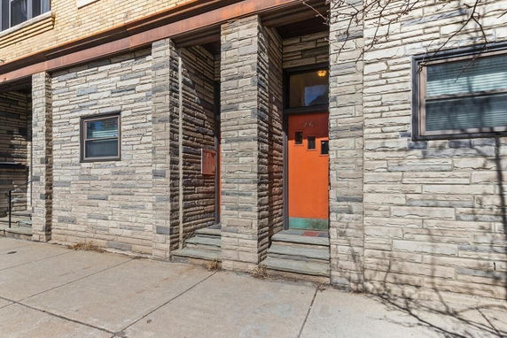 Front view of a building with brick facade and orange door.