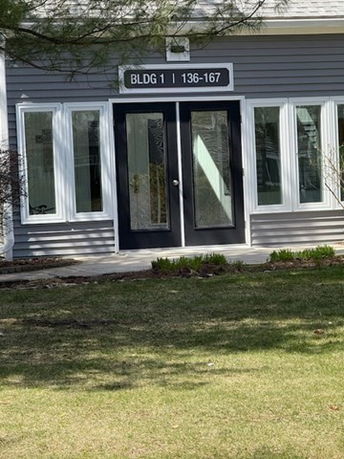 Front view of a building entrance with double glass doors and multiple windows.