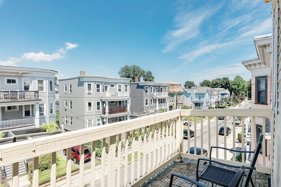 View from a balcony overlooking a street with multiple residential buildings.