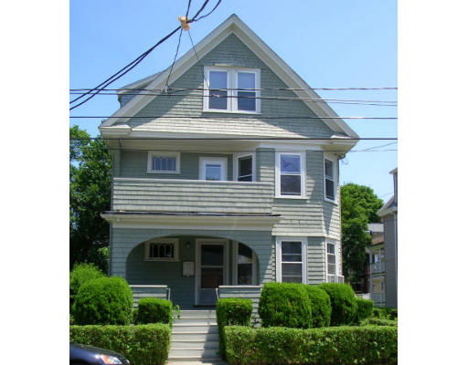 Front view of a three-story house with a gable roof and front porch.