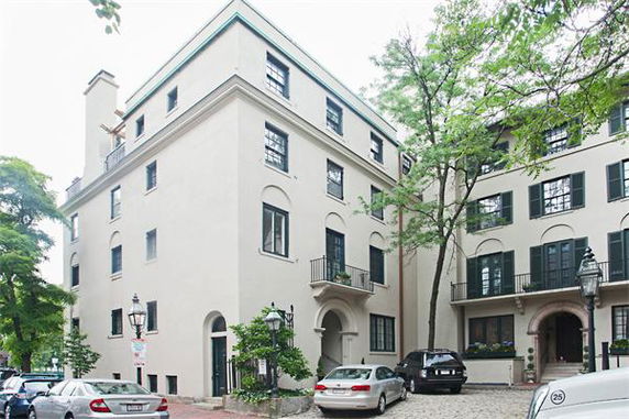 Front view of a multi-story building with arched windows and a small balcony.