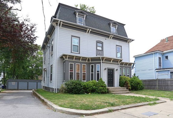 Front view of a two-story house with a distinctive roof and columns at the entrance.