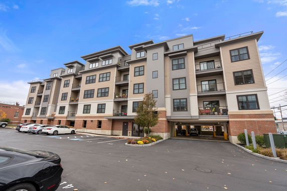 Front view of a multi-story apartment building with parking underneath.