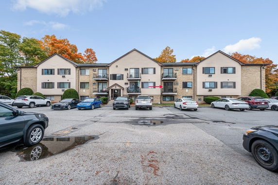 Front view of a multi-story apartment building with parking area.