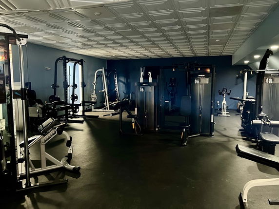 Indoor gym area with various exercise machines and equipment.