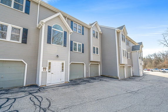 Front view of a multi-story building with garages on the ground level.