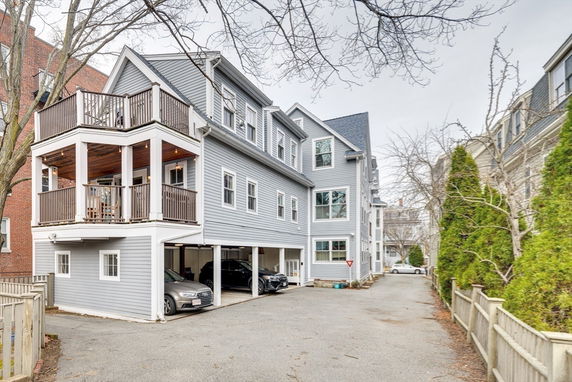 Front view of a multi-story house with exterior balconies and a covered parking area.
